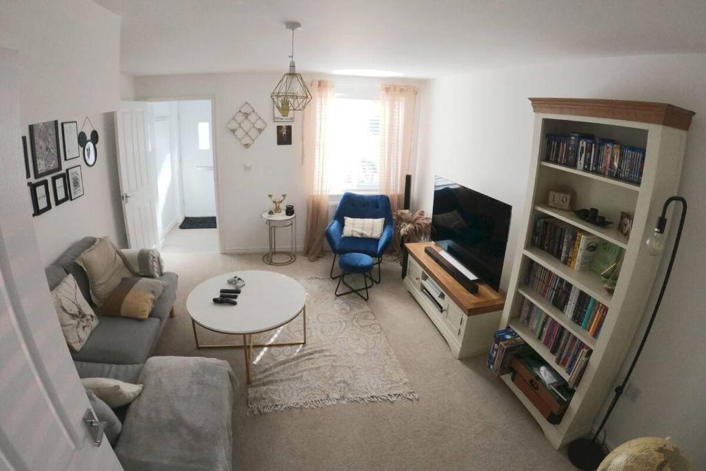 een woonkamer met een bank, een tafel en een tv bij Cosy townhouse near Kidwelly in Kidwelly
