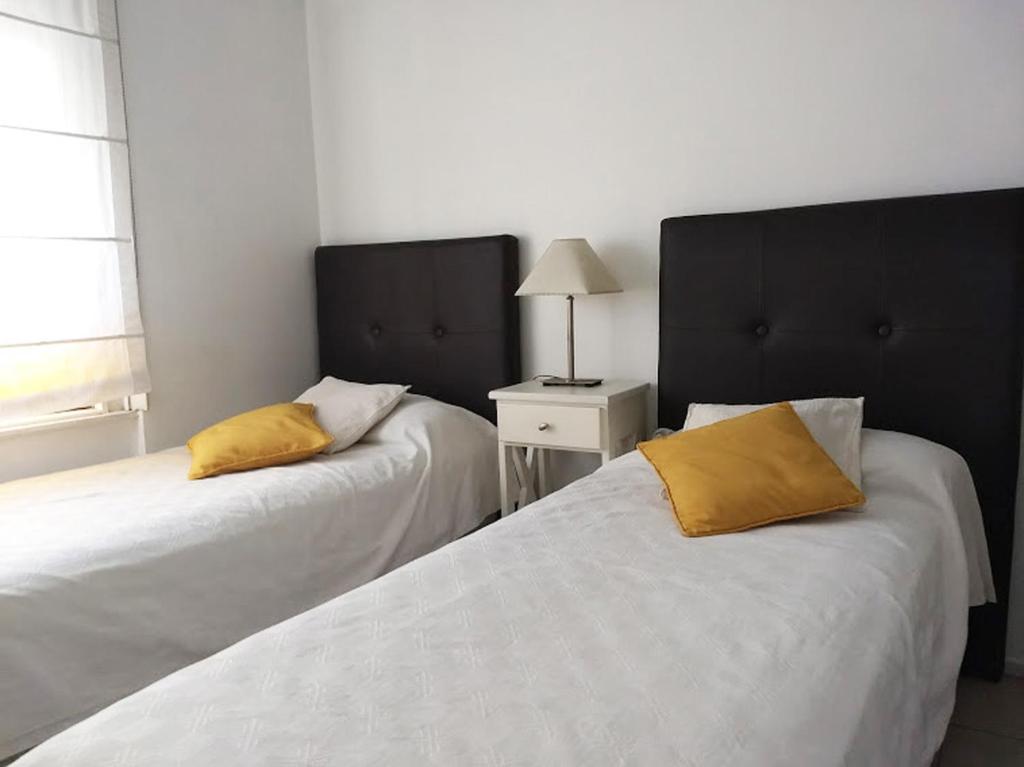 two beds with yellow pillows in a bedroom at Departamento de dos dormitorios para 6 personas en el centro in Buenos Aires