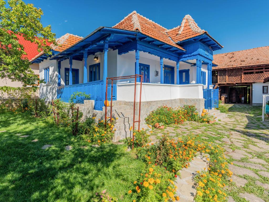 une maison bleue et blanche avec des fleurs dans la cour dans l'établissement Casa de vacanta traditionala romaneasca, à Schiuleşti