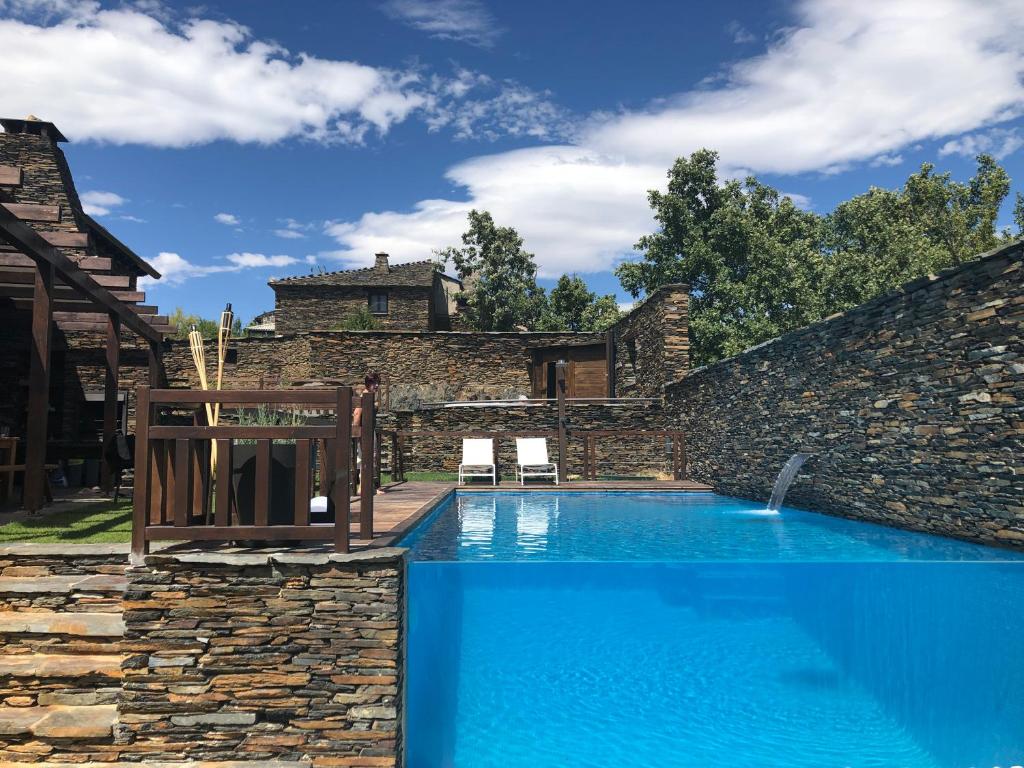 a swimming pool in a yard with a stone wall at Casa del Ocejón in Majaelrayo