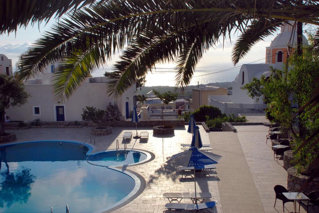 a pool with chairs and umbrellas next to a building at Anatoli Hotel & Spa in Fira