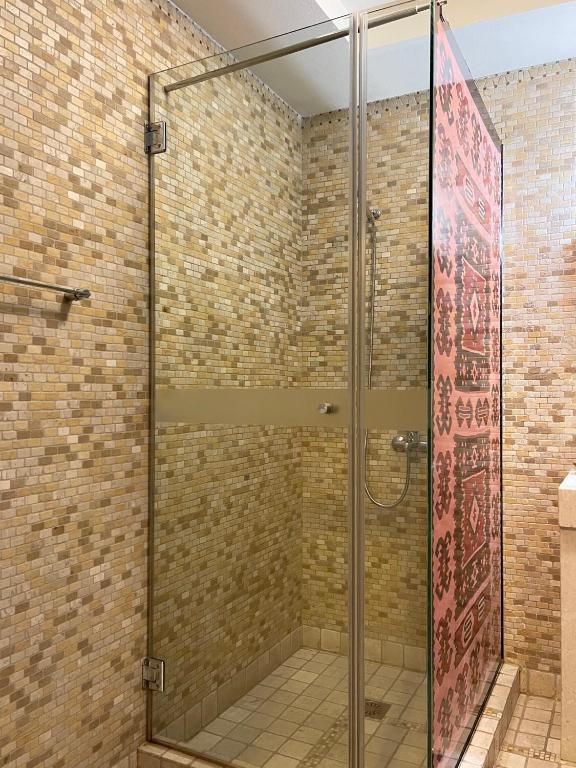 una doccia in vetro in un bagno con parete di mattoni di Hotel Mangalemi a Berat