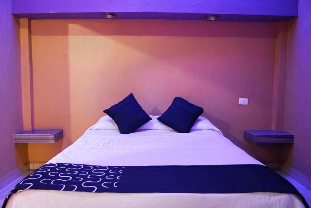 a bedroom with a large bed with two blue pillows at Hotel Oasis in Monterrey