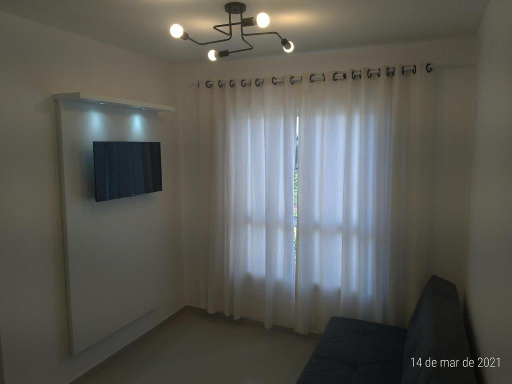a living room with a white curtain and a tv at AP 2 dormitórios NOVO em Montenegro edif Malta 302 in Montenegro