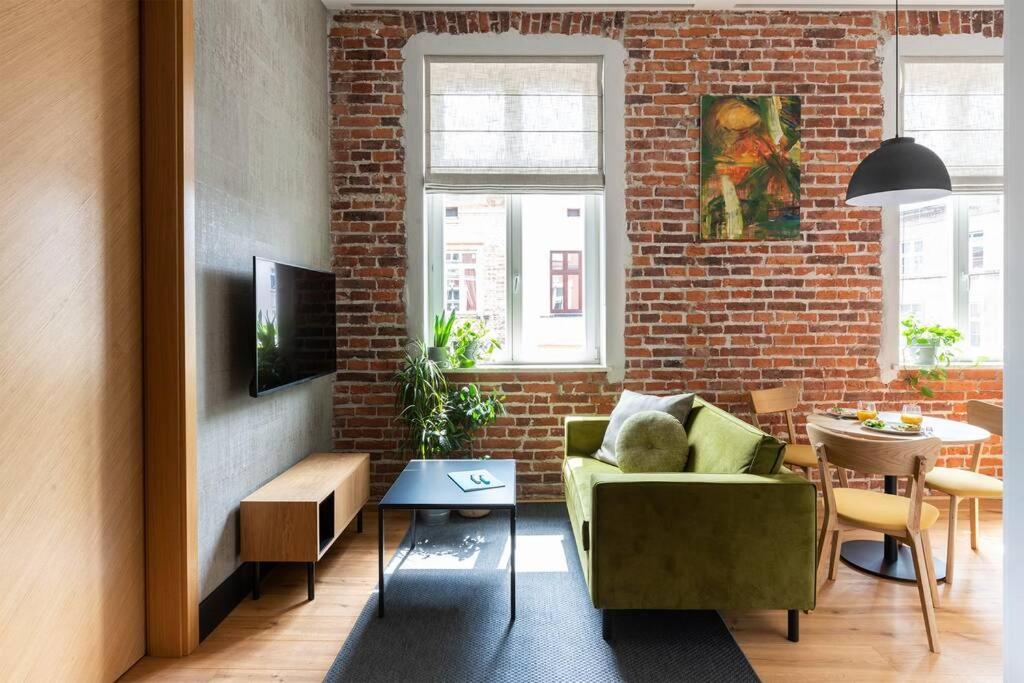 - un salon avec un canapé vert et un mur en briques dans l'établissement Elegant Apartment Luminis in Krakow's Old City, à Cracovie