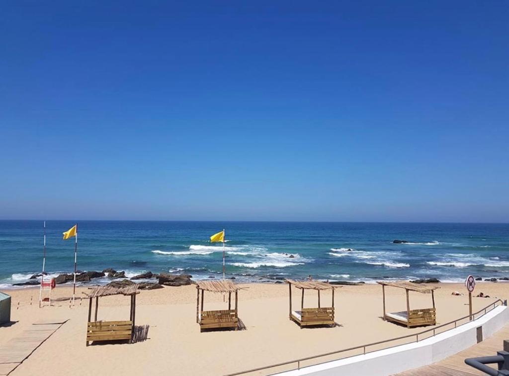 a row of chairs on a beach with the ocean at Silver Coast Beach House in Torres Vedras