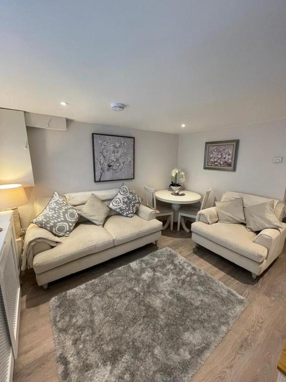 a living room with two couches and a table at Dancy Mews Over 30's Only apartment in Tavistock