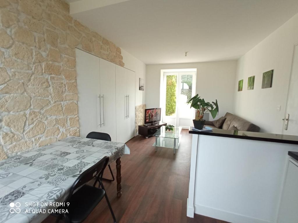 sala de estar con mesa y pared de piedra en LE P'tit logement de lor'Phée en Chantepie