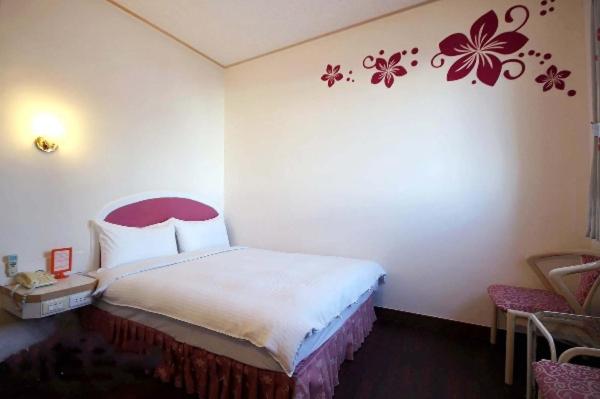 um quarto com uma cama com uma flor vermelha na parede em Traveler Hotel Taitung em Taitung City