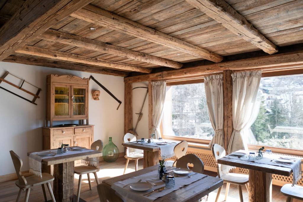 uma sala de jantar com mesas, cadeiras e janelas em B&B Il Tabià em Pieve di Cadore