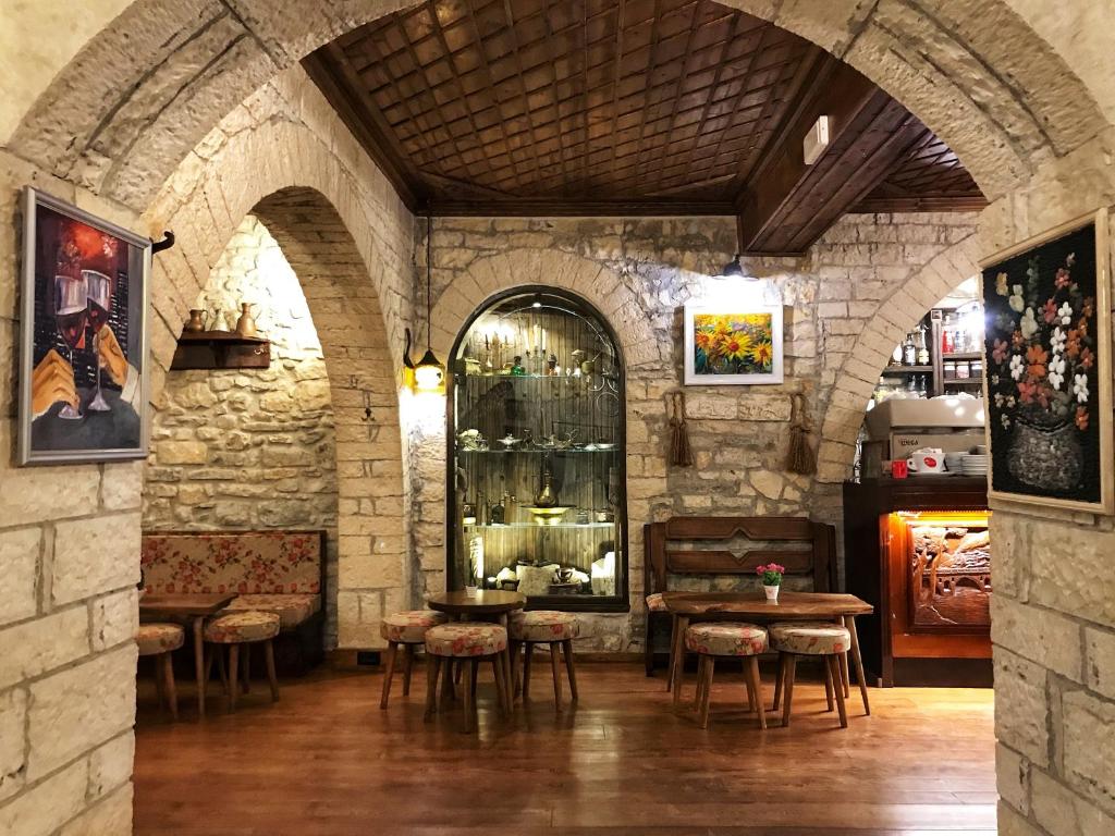 Zimmer mit einer Steinmauer mit einem Tisch und Stühlen in der Unterkunft Hotel Mangalemi in Berat