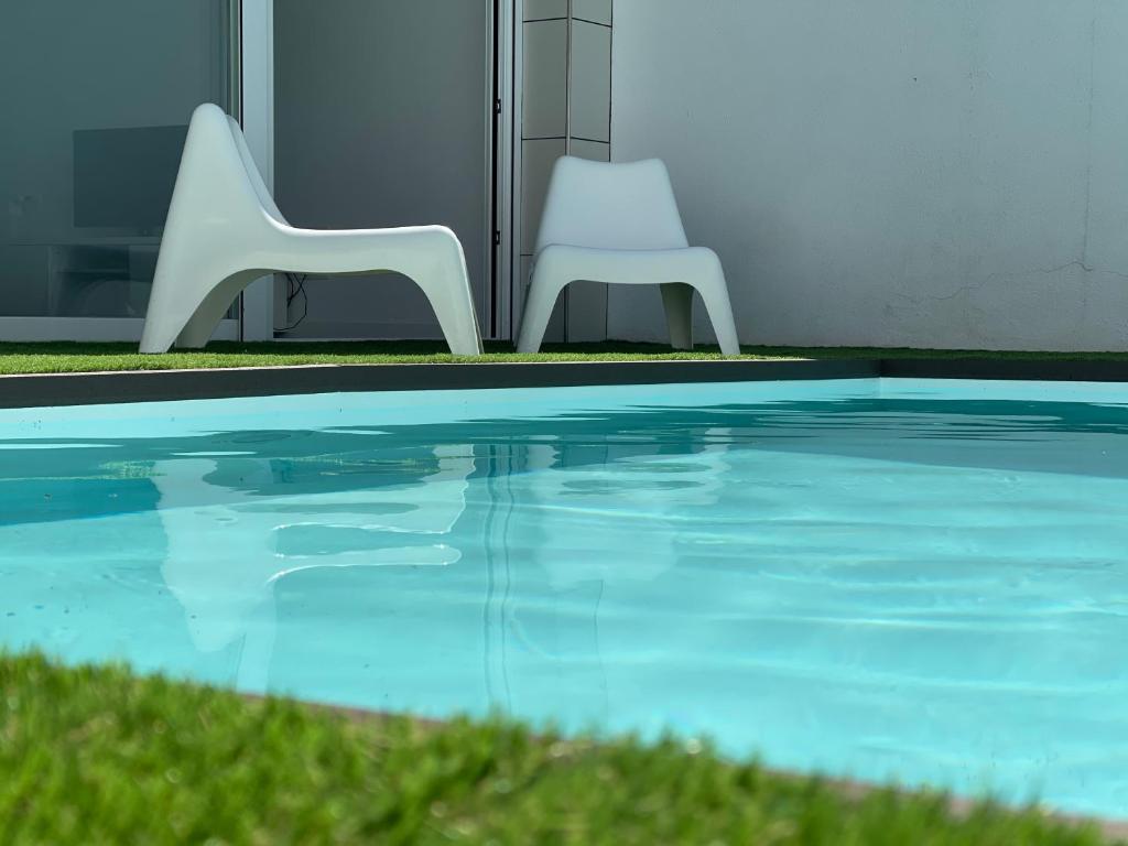 two white chairs sitting next to a swimming pool at Casa en CARABAÑA a 30 minutos de MADRID in Carabaña