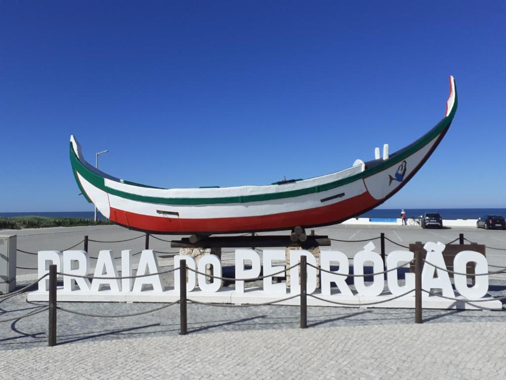 Una señal para una playa con un barco. en Praia do Pedrógão, en Pedrógão