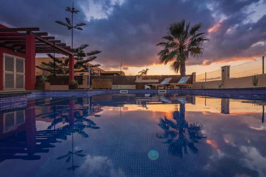a swimming pool with a sunset in the background at VILLA NELLY in Costa de Antigua