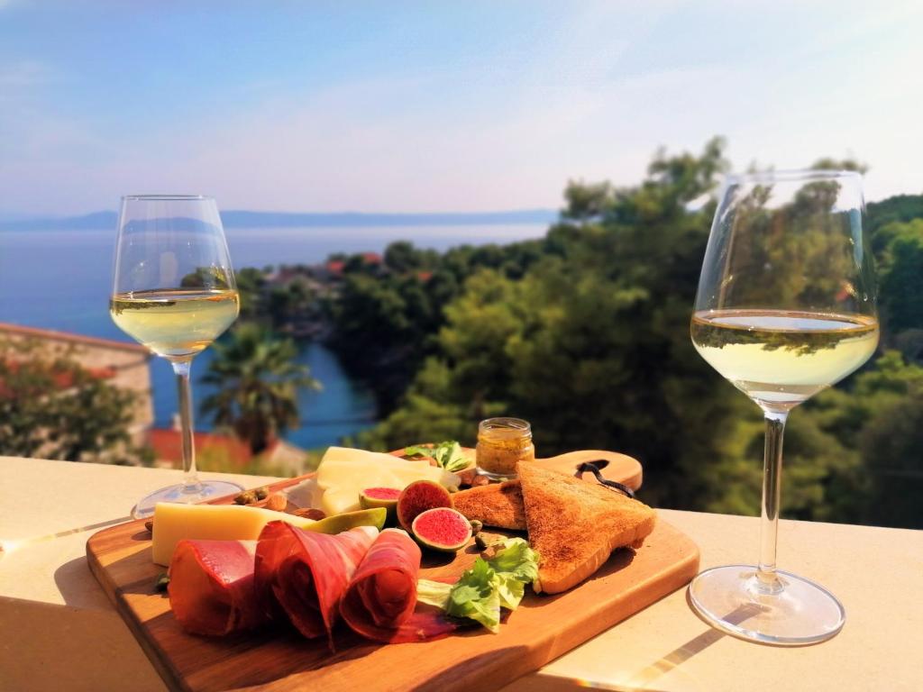 a plate of food and two glasses of wine at Sea View Apartments in Selca