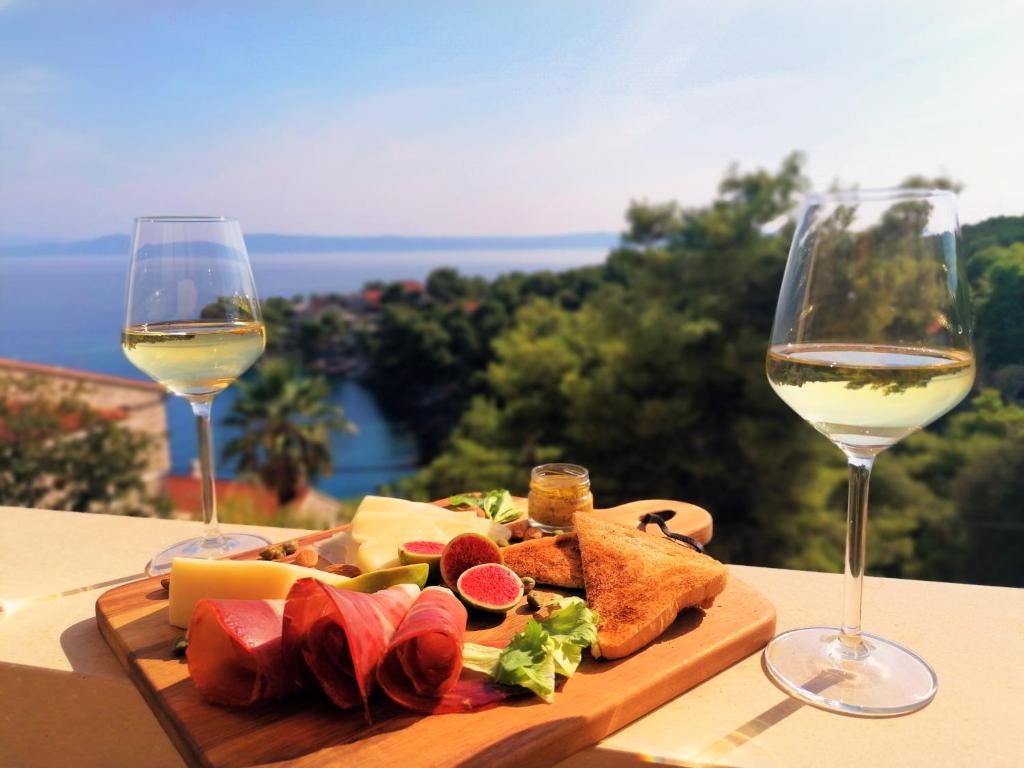 a plate of food and two glasses of wine at Sea View Apartments in Selca