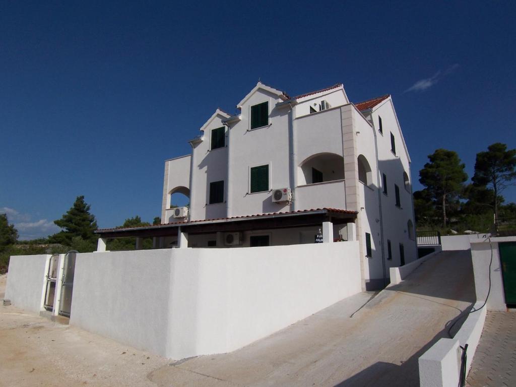 a white house behind a white fence at Apartments Croatia Brač in Supetar