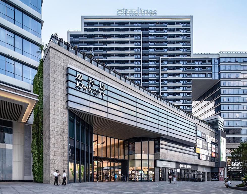 东莞东莞馨乐庭松山湖公寓酒店的一座大型建筑,前面有人