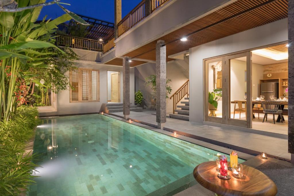 une piscine intérieure avec une table et une maison dans l'établissement Villa Daun 1 Canggu by Premier Hospitality Asia, à Canggu