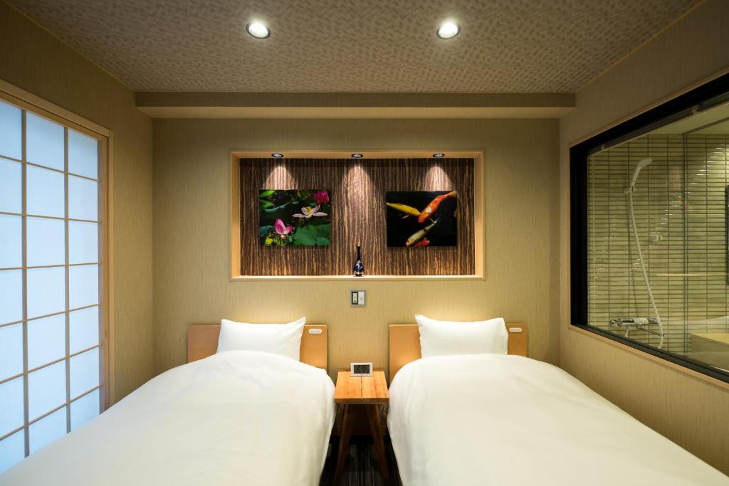 2 Betten nebeneinander in einem Zimmer in der Unterkunft Shiki Suites - Kyoto Umekoji in Kyoto