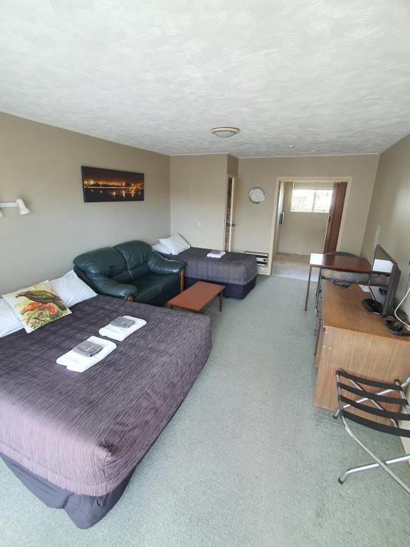 Habitación con cama, sofá y sala de estar. en Ascot Motor Lodge, en Westport