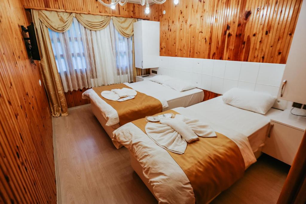 two beds in a room with wooden walls at SÜMELA HOLİDAY HOTEL in Macka
