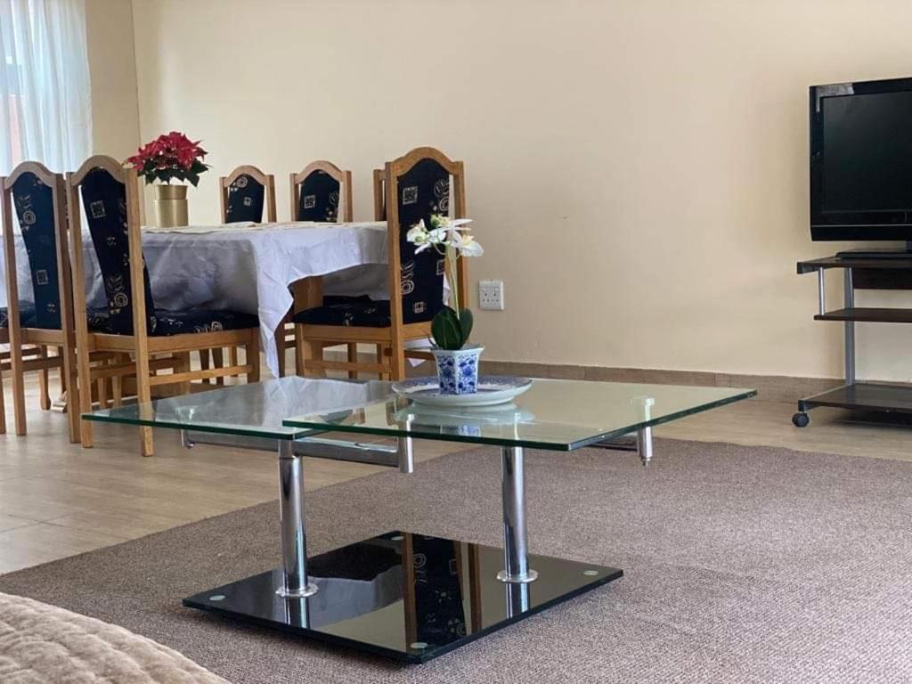 sala de estar con mesa de cristal y comedor en Elegant84, en Johannesburgo