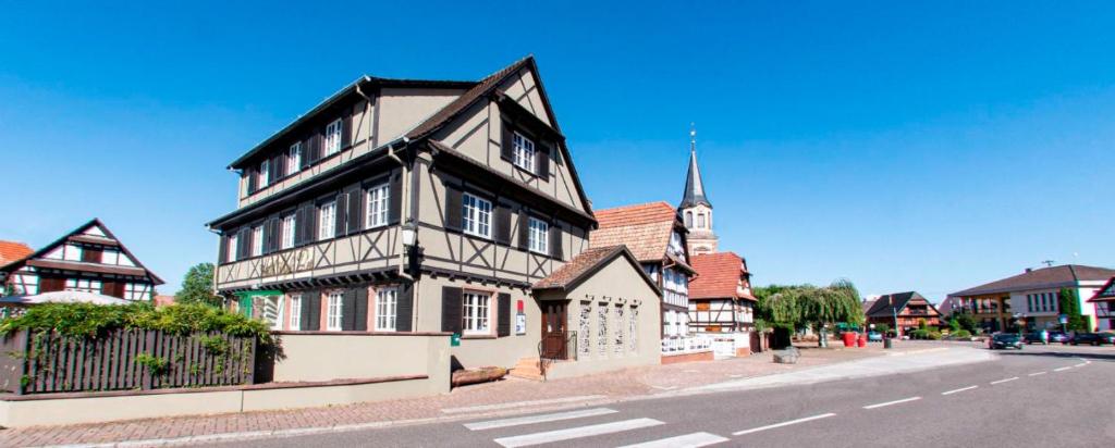 - un bâtiment noir et blanc dans une rue avec une église dans l'établissement Aigle d'Or - Strasbourg Nord, à Reichstett