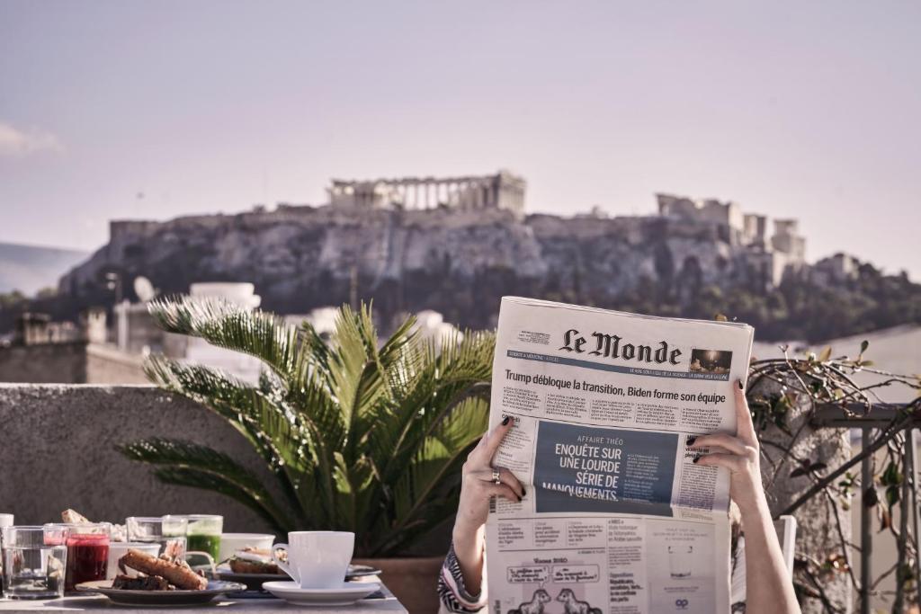 a person sitting at a table reading a newspaper at Asomaton in Athens