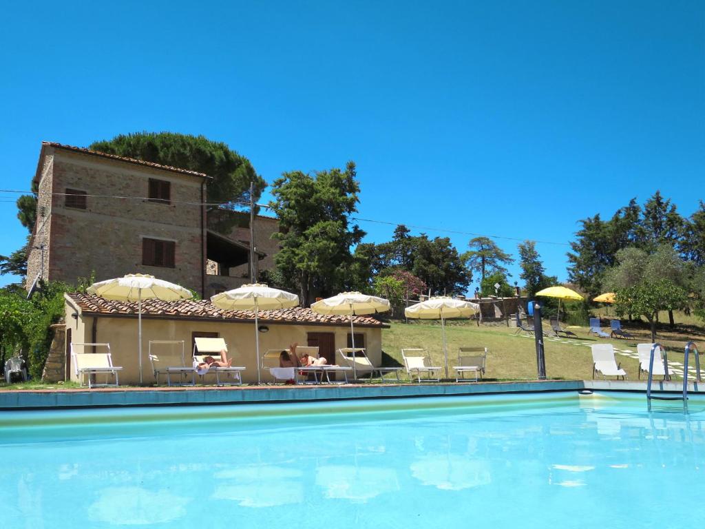 einem Pool mit Stühlen und Sonnenschirmen vor einem Gebäude in der Unterkunft Holiday Home Villa Caggio-4 by Interhome in Volterra