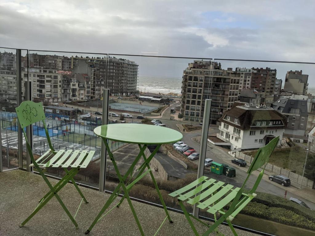 a table and chairs on a balcony with a view of a city at STUDIO MET FRONTAAL ZEEZICHT in Middelkerke