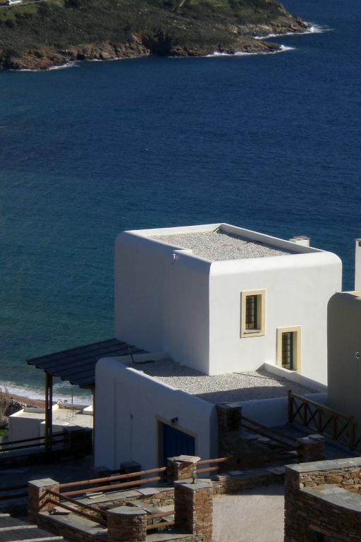a white building with the ocean in the background at Monolithos Villas in Kipri