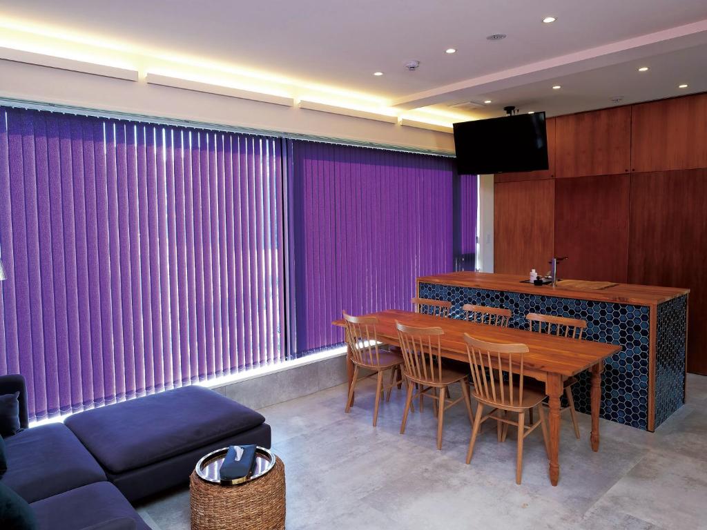 a dining room with purple curtains and a table and chairs at CHULAX OKINAWA YOMITAN【Designer Condominium Hotel】 in Yomitan