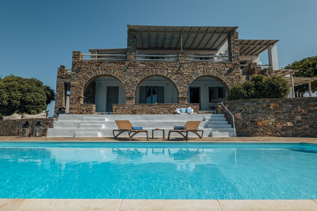 a pool with two chairs and a house at Terra in Parikia