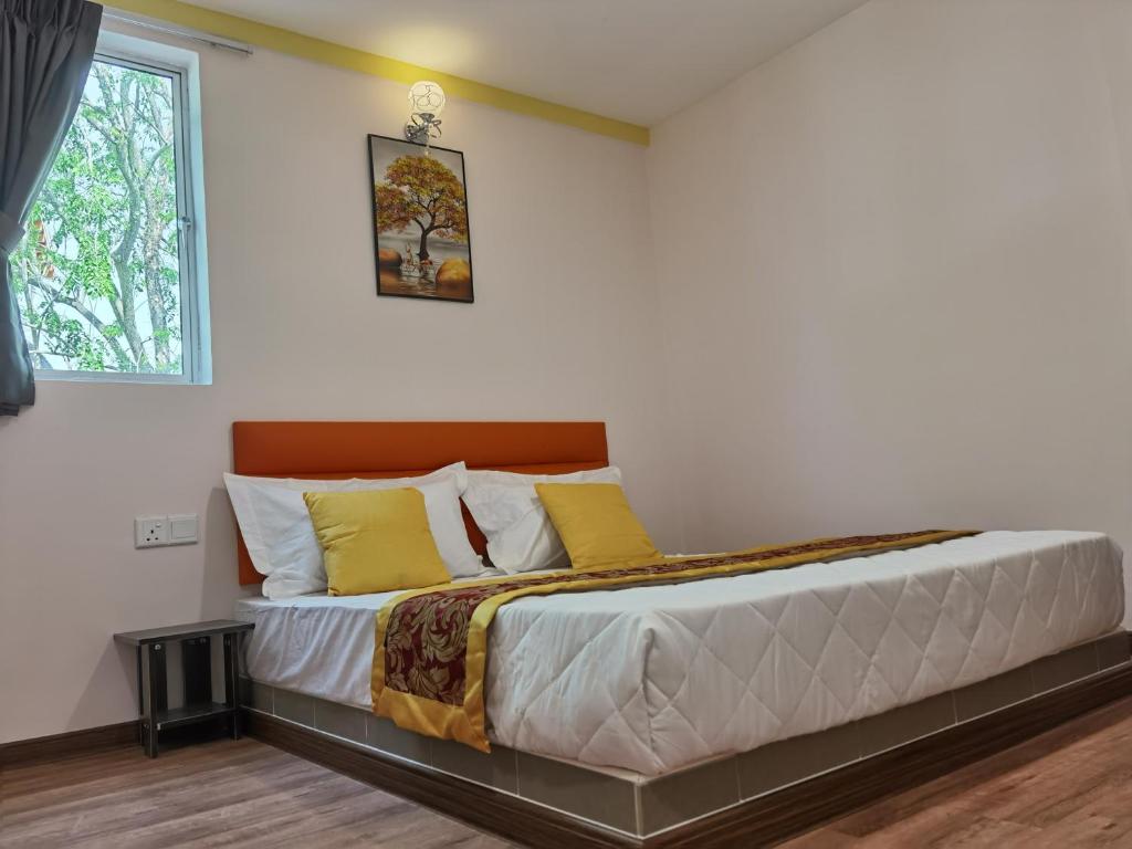 een slaapkamer met een bed met gele kussens en een raam bij MORNINGS HOTEL in Sungai Petani