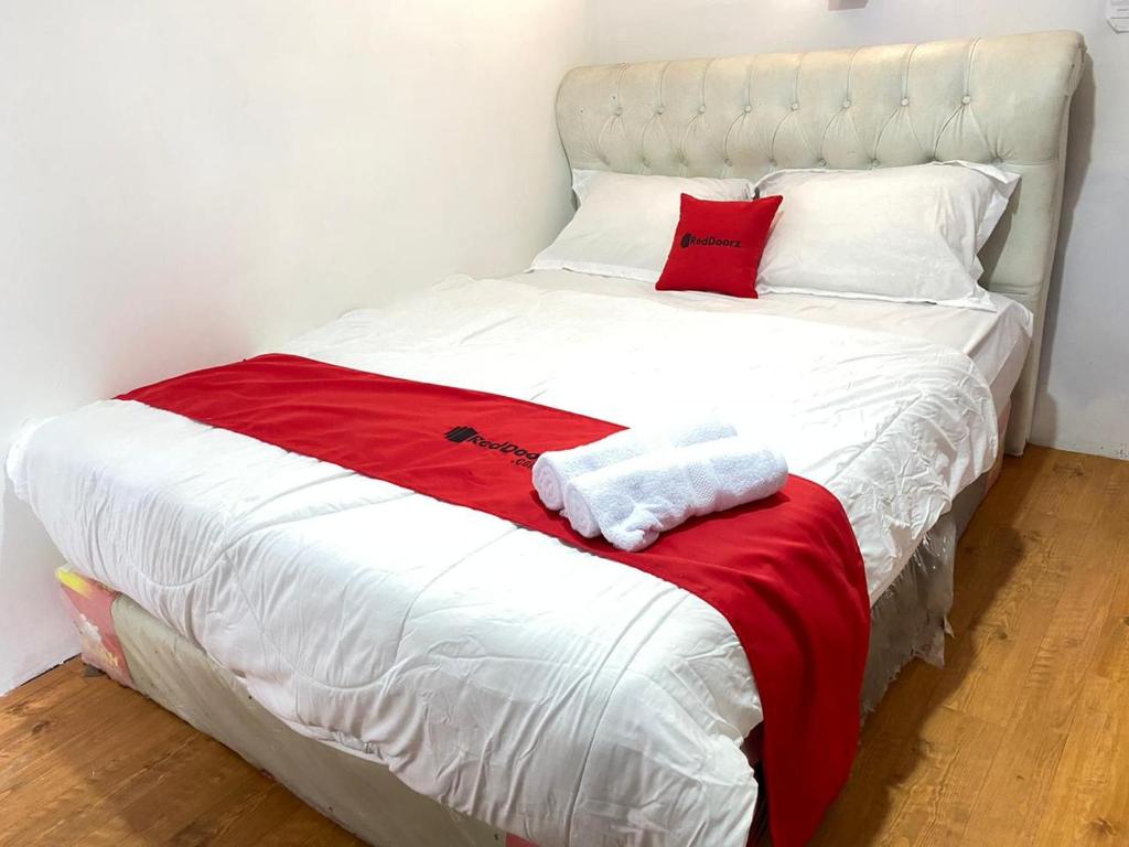 Una cama blanca con toallas rojas y blancas. en RedDoorz Plus @ Puncak Mas Cottage en Lampung