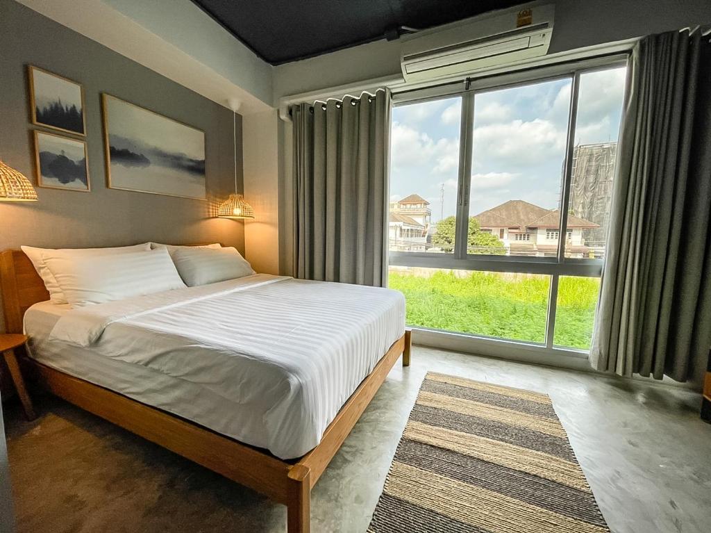 - une chambre avec un lit et une grande fenêtre dans l'établissement Bedgasm Hostel Chanthaburi, à Chanthaburi