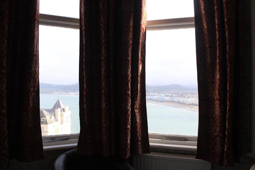 a window with a view of a beach and the ocean at Headlands Hotel in Llandudno