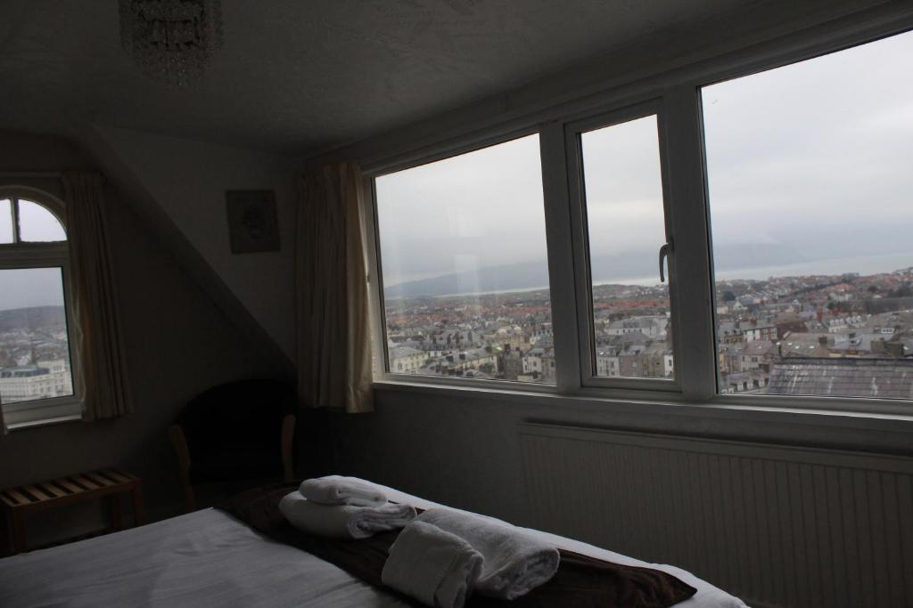 a bedroom with a bed in front of windows at Headlands Hotel in Llandudno