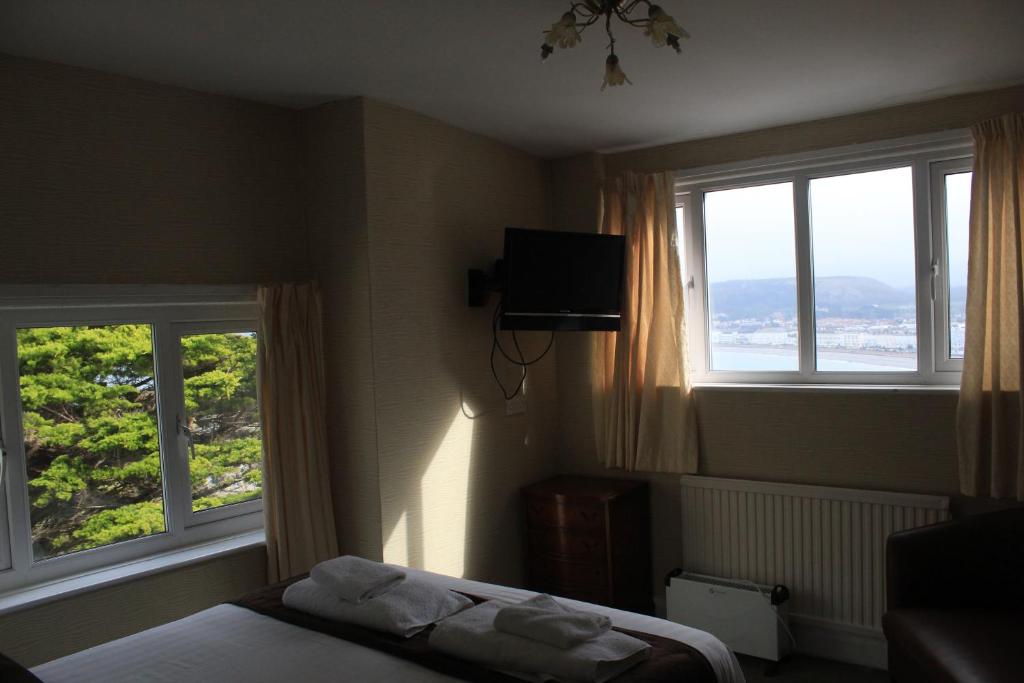 a bedroom with two windows and a bed with towels at Headlands Hotel in Llandudno