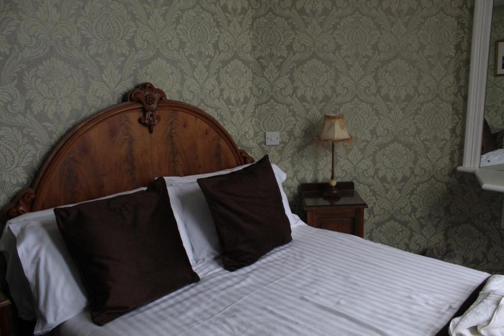a bed with a wooden headboard in a bedroom at Headlands Hotel in Llandudno
