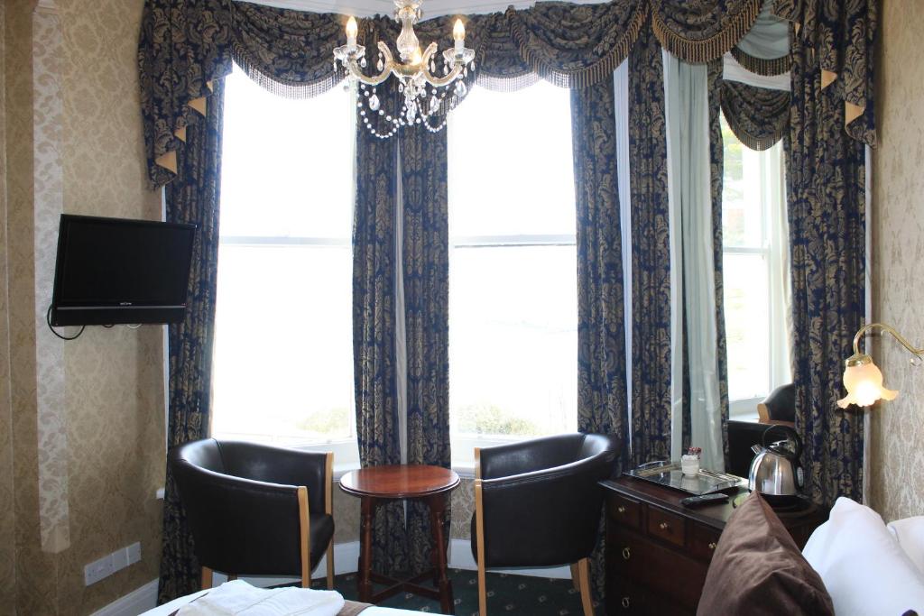 a hotel room with a table and chairs and a window at Headlands Hotel in Llandudno