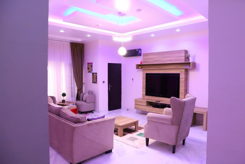 a living room with purple walls and a tv and chairs at Rhodabode Apartments. A Luxury 3 bedroom bungalow. in Abuja