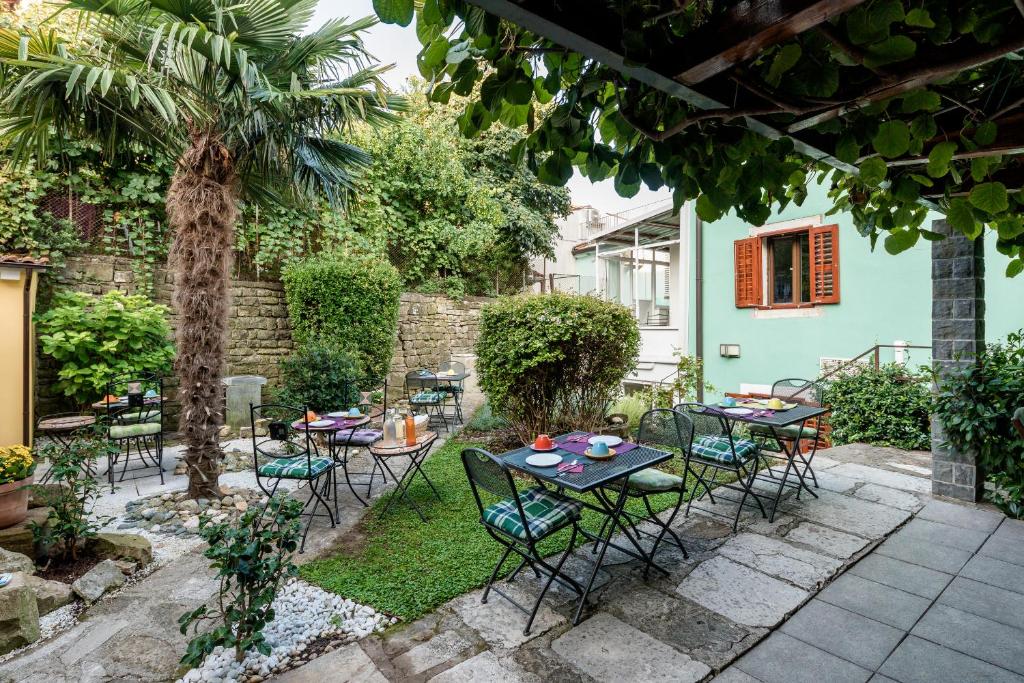 a patio with tables and chairs and a palm tree at Miracolo di Mare Retro in Piran