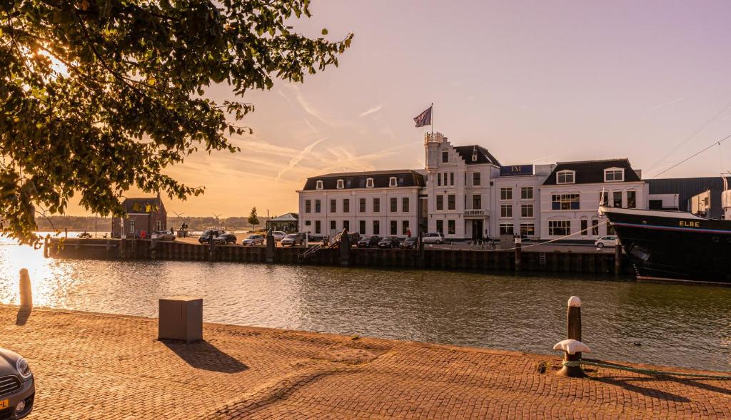 a large white building next to a body of water at Hotel Maassluis in Maassluis
