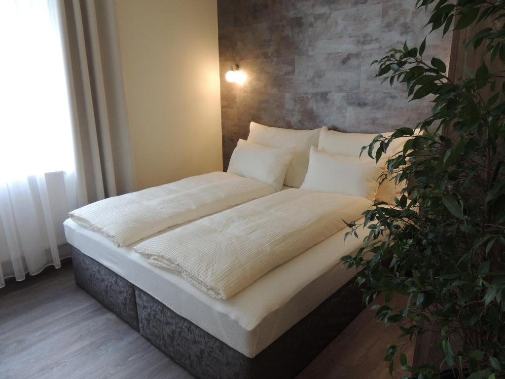 1 cama con sábanas blancas y almohadas en una habitación en Apartmány I - KAfe Bojnice, en Bojnice