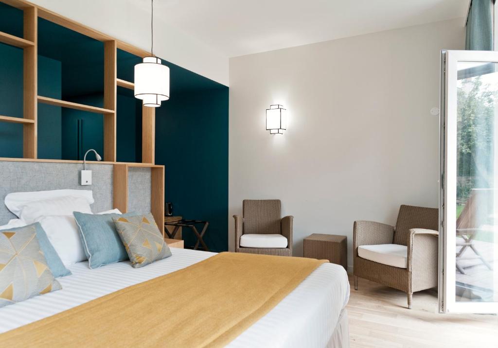 a bedroom with a large bed and two chairs at Hôtel Les Costans, The Originals Relais in Perros-Guirec
