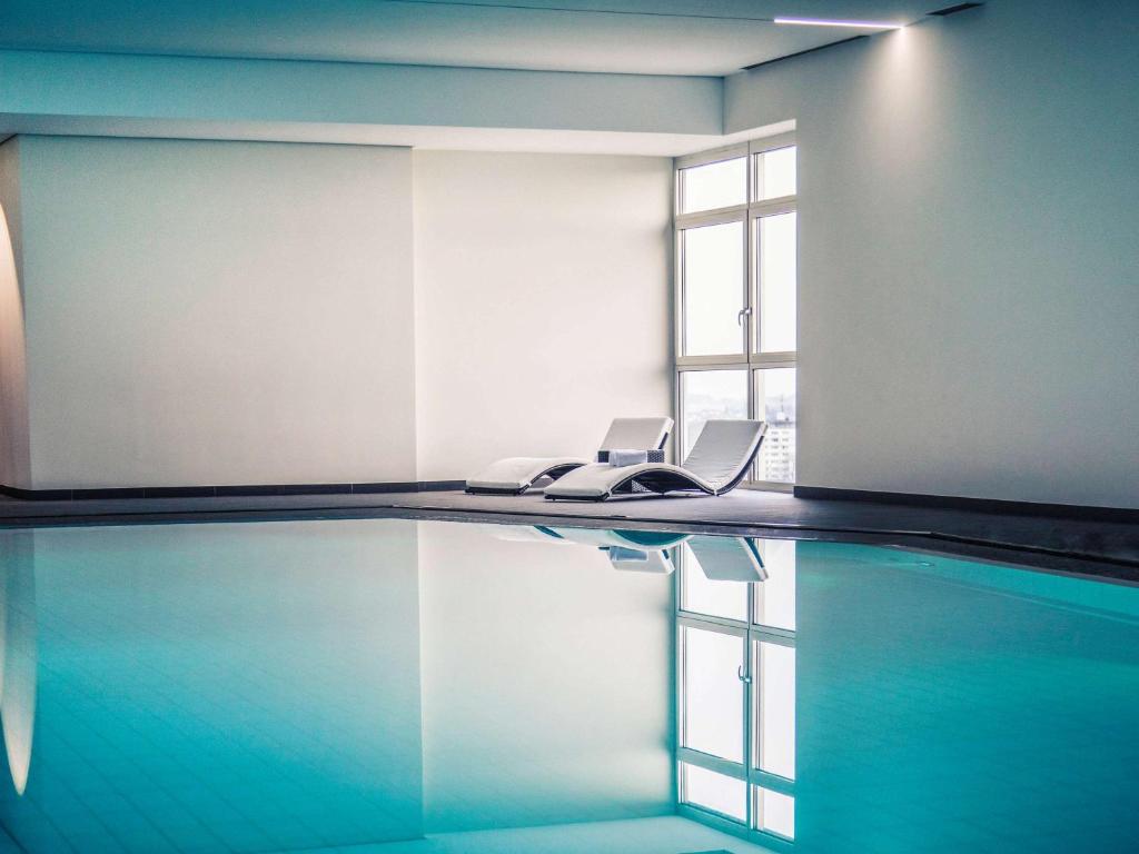 a swimming pool with two chairs and a window at Mercure Hotel Lüdenscheid in Lüdenscheid
