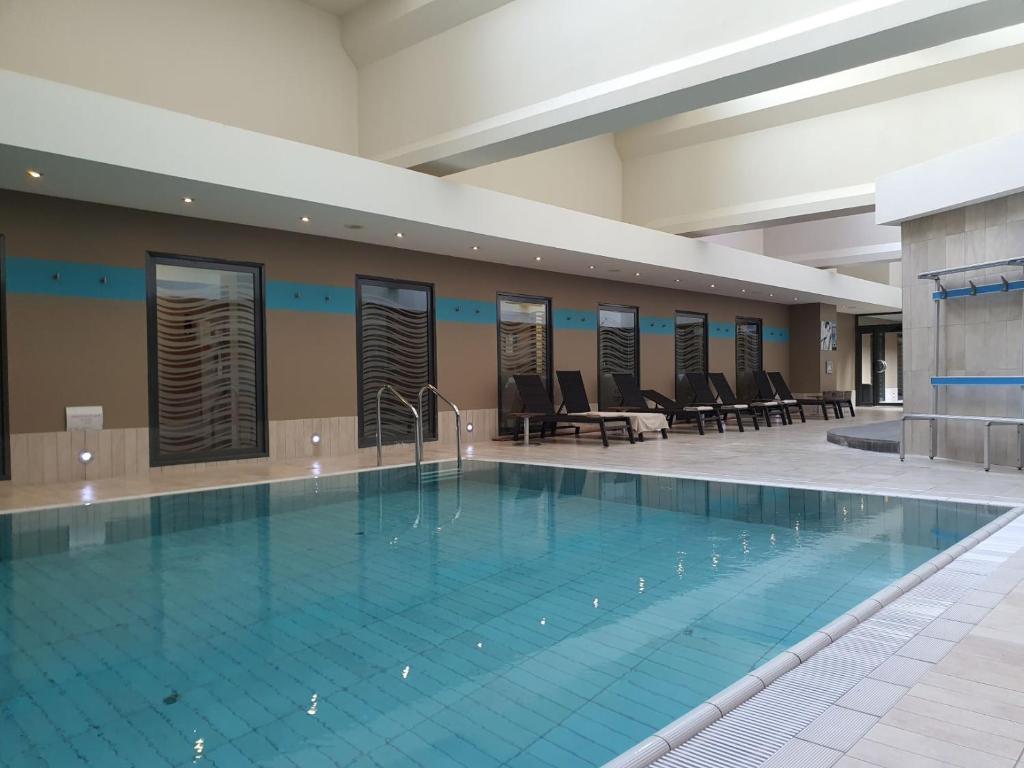 a large swimming pool in a building with chairs and tables at Hotel Spa Le Pasino in Le Havre
