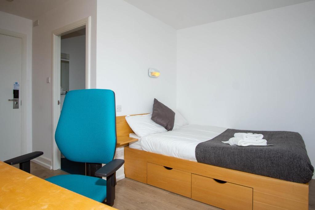 - une chambre avec un lit et une chaise bleue dans l'établissement Dromroe Village University of Limerick, à Limerick